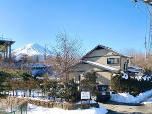 une maison avec une montagne enneigée en arrière-plan dans l'établissement 富士の樱House 宝栄, à Fujikawaguchiko