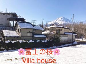 un groupe de maisons dans la neige avec une montagne dans l'établissement 富士の樱House 宝栄, à Fujikawaguchiko