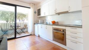 a kitchen with white cabinets and a view of a patio at CANADELL BLOC B baixos 1ª in Calella de Palafrugell +4 photos