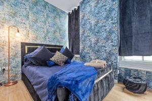 a bedroom with a bed with blue wallpaper at Luxury Two Bedroom Flat right opposite to Harrods KB15 in London