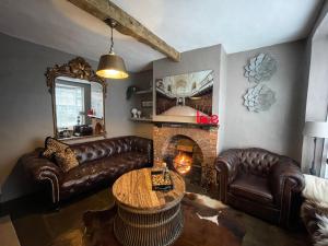 a living room with leather couches and a fireplace at 3-storey luxury Georgian house, High St, Henley-in-Arden in Henley in Arden