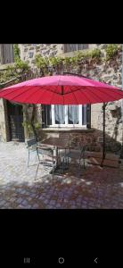 uma mesa e cadeiras sob um guarda-sol vermelho em Studio dans maison individuelle - chemin Stevenson em Le Puy-en-Velay