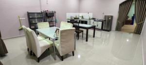 Un comedor con mesa y sillas y una cocina. en Homestay Azihan, en Pasir Puteh
