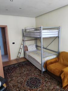 a bunk bed with a ladder and a couch in a room at Rila Apartment in Samokov
