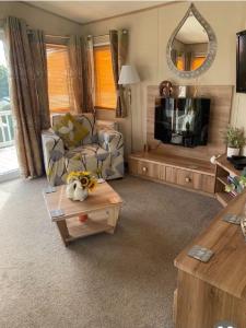 sala de estar con sofá y mesa en Beautiful Caravan With Decking At Hoburne Devon Bay, Ref 54058f en Paignton