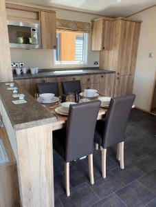 a kitchen with a wooden table with chairs around it at Beautiful Caravan With Decking At Hoburne Devon Bay, Ref 54058f in Paignton