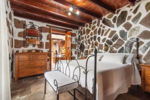 um quarto com uma cama e uma parede de pedra em El patio canario em Firgas