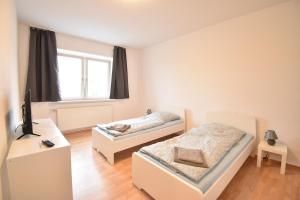 a bedroom with two beds and a desk and a window at CoreRooms - Apartment Bochum Wattenscheid in Bochum