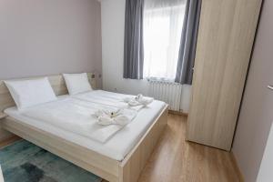 a bedroom with a white bed with white flowers on it at Maple Tree Budget Apartments in Budapest