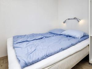 a bed with blue sheets in a white room at Holiday home Bogense XLV in Bogense