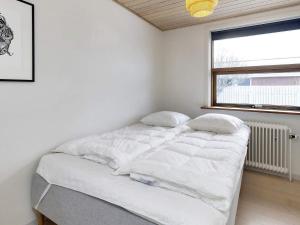 a bed in a white room with a window at Holiday home Skagen XXXVI in Skagen