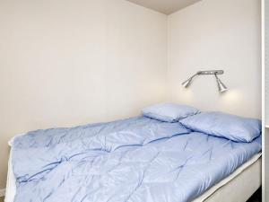 Holiday home Bogense XLVIII في بوجنسي: سرير مع وسائد زرقاء في الغرفة