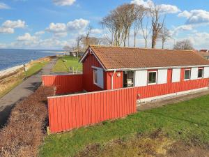 un edificio rojo y blanco junto al agua en Holiday home Bogense XLVI, en Bogense