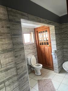 uma casa de banho com um WC e uma porta de madeira em Balfour Lodge em Balfour