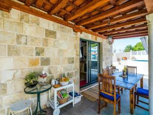 un patio con mesa, sillas y pared de piedra. en Dubrovnik Chalets en Čilipi