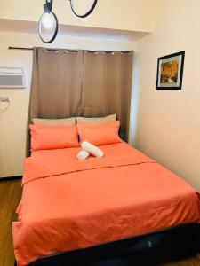 a teddy bear laying on a bed with orange pillows at City Homes: The Radiance Manila Bay in Manila