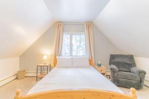 a bedroom with a bed and a chair and a window at The Cozy Harriet Log Home in Fairbanks