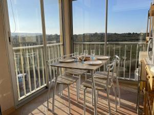 een tafel met stoelen en wijnglazen op een balkon bij Appartement Fleury-Saint-Pierre-la-Mer, 3 pièces, 5 personnes - FR-1-229D-268 in Fleury