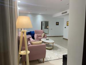 a living room with pink chairs and a lamp at Gold crest Mall & Residence in Lahore