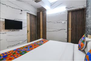 a bedroom with a bed and a tv on a wall at FabExpress Subh Residency in Sāntrāgāchi