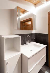 a white bathroom with a sink and a mirror at Chalet Edelweiß in Saalbach-Hinterglemm