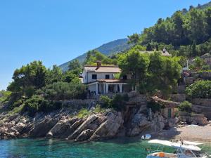 een huis op een klif met een boot in het water bij Robinson Ane in Gdinj