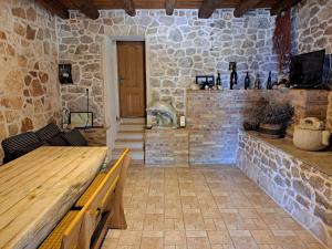 een kamer met een houten tafel en een stenen muur bij Robinson Ane in Gdinj