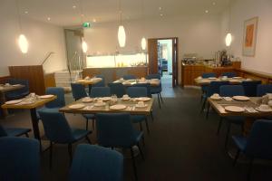 een eetkamer met houten tafels en blauwe stoelen bij Hotel Senator München in München