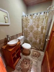 a bathroom with a toilet and a shower curtain at Cabañas “La India” in Jardín América