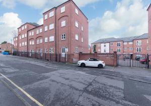 a white car parked in front of a brick building at Derby Parliament Spacious 2Bedroom Apartment with Parking in Derby