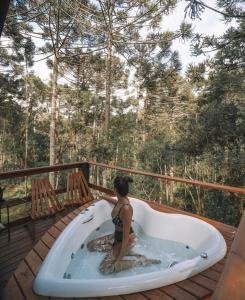 a woman sitting in a bath tub on a deck at Cambará Ecomoradas in Cambara do Sul