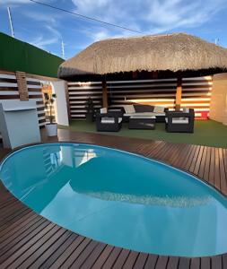 a swimming pool on a deck with a thatch roof at Casa de Praia Tibau-RN in Tibau
