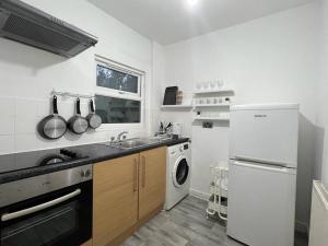 een witte keuken met een wastafel en een vaatwasser bij Studio with Bathroom and Kitchen 20 minutes from Central London in Londen