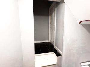 pasillo con puerta abierta y suelo de baldosa negra en Studio with Bathroom and Kitchen 20 minutes from Central London en Londres