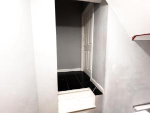un couloir avec une porte ouverte et du carrelage noir au sol dans l'établissement Studio with Bathroom and Kitchen 20 minutes from Central London, à Londres