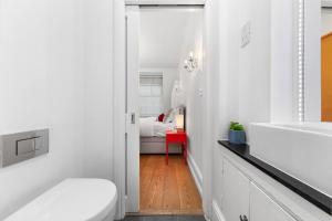 a white bathroom with a toilet and a bedroom at 1BR Harrods Hydepark Knightsbridge KB91 in London