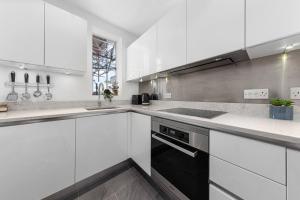 a white kitchen with a sink and a stove at 1BR Harrods Hydepark Knightsbridge KB91 in London