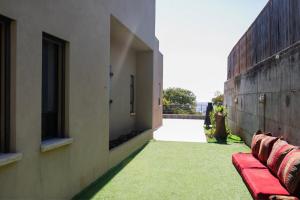 een patio met een rode bank en groen gras bij וילה חלום יעקב- וילה מקסימה בחצור הגלילת in Hatzor haglilit