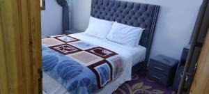 ein Bett mit einer Decke und Kissen darauf in der Unterkunft ADAM APPARTEMENTS in Ad-Dakhla