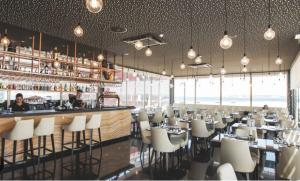 a restaurant with a bar with white chairs and tables at Durma a bordo de um veleiro moderno em Oeiras in Oeiras