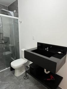 uma casa de banho com um lavatório preto e um WC. em Pousada Jurerê Rural em Florianópolis