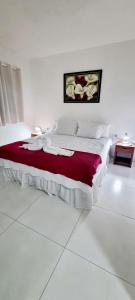 um quarto branco com uma cama com um cobertor vermelho em Pousada Peromar em Maragogi