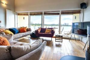 a living room with couches and a flat screen tv at Clearwater 31, The Lakehouse in Somerford Keynes