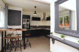 a kitchen with black cabinets and stools and a mirror at Le Saint-Brice in Chartres