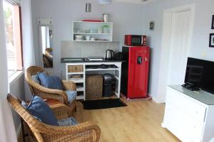 a living room with chairs and a red refrigerator at Weaver Cottage in Chintsa East on the Wild Coast in Cintsa