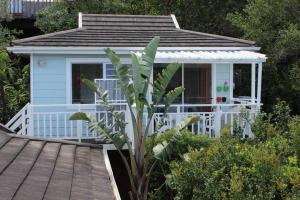 a small blue house with a porch and a wooden deck at Weaver Cottage in Chintsa East on the Wild Coast in Cintsa