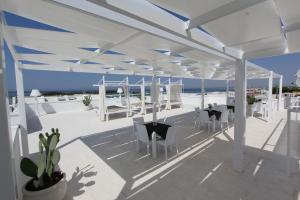 a pavilion with white chairs and tables and the ocean at Hotel Paladini in Porto Cesareo