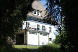 ein weißes Haus mit einem Balkon an der Seite in der Unterkunft Haus Dupont in Winterberg