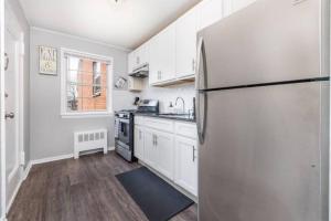 uma cozinha com armários brancos e um frigorífico em Queen Bed Apt - Fully Furnished with Max Amenities em West Hartford