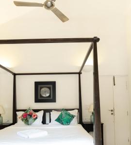 a bedroom with a canopy bed with a ceiling fan at Villa Olive goa ( OV private pool villas ) in Mapusa